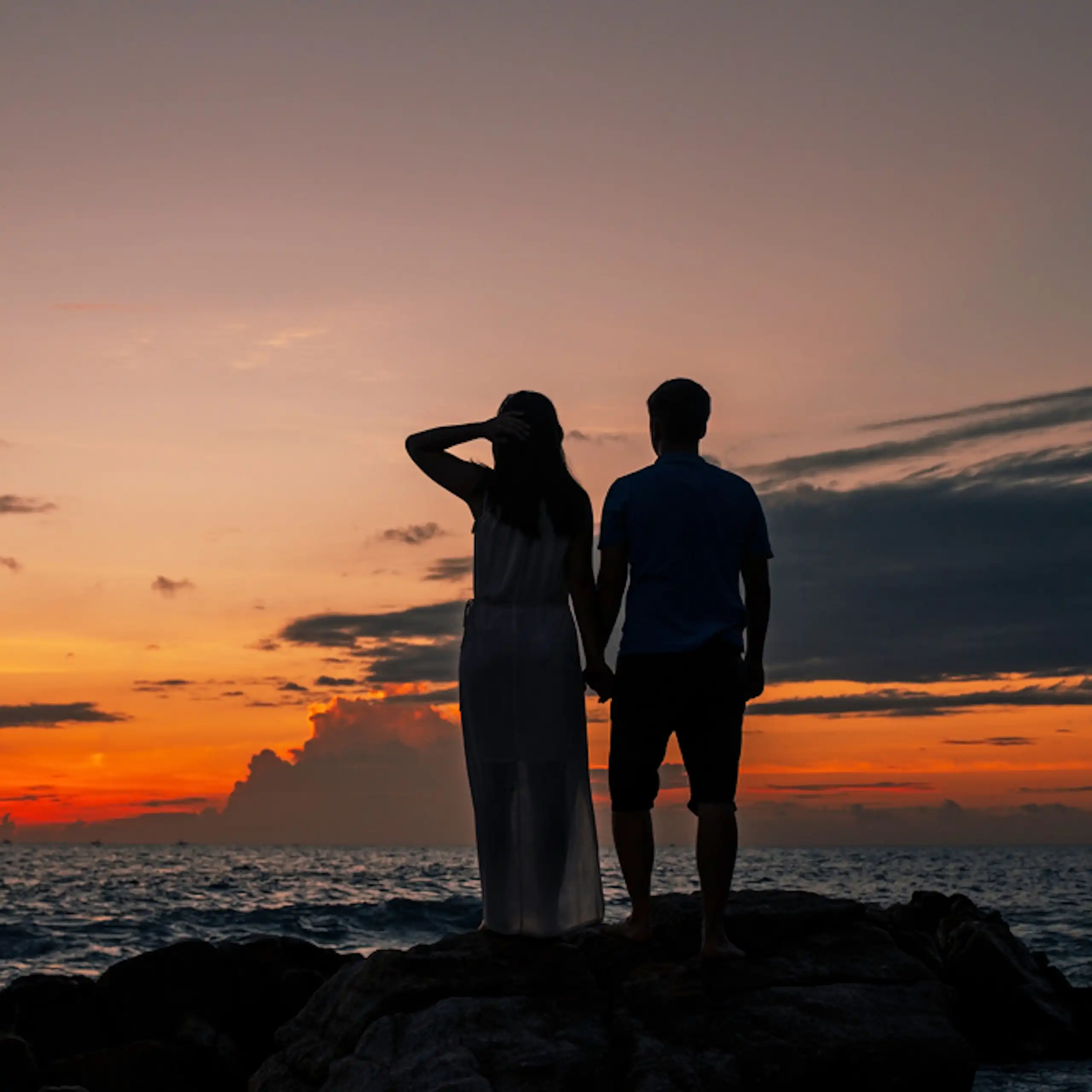 Silhouette de couple adolescent sur une plage au coucher de soleil