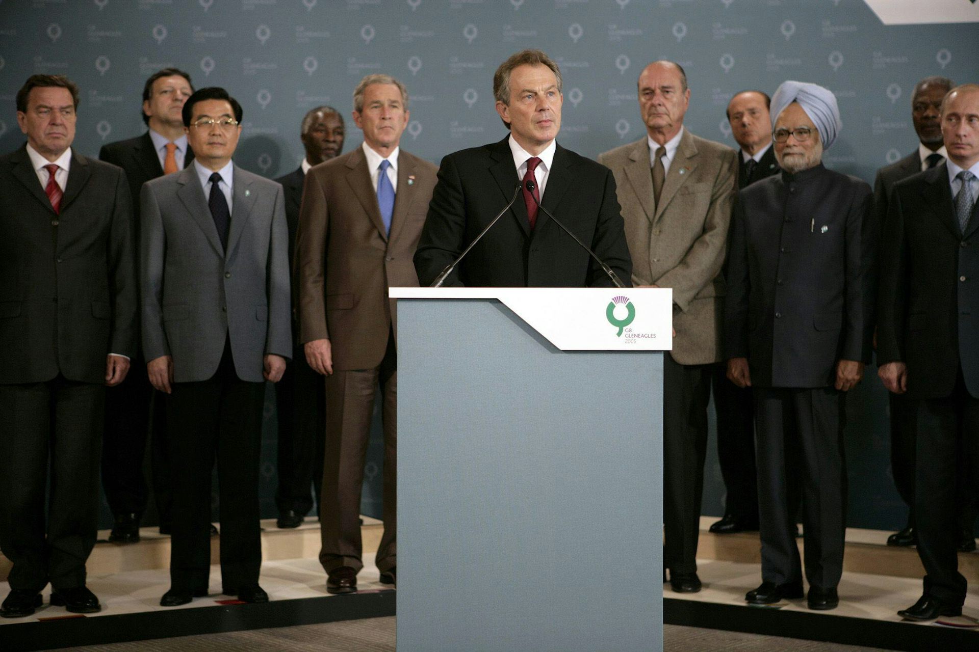 Blair speaks at a podium, with other world leaders standing behind him
