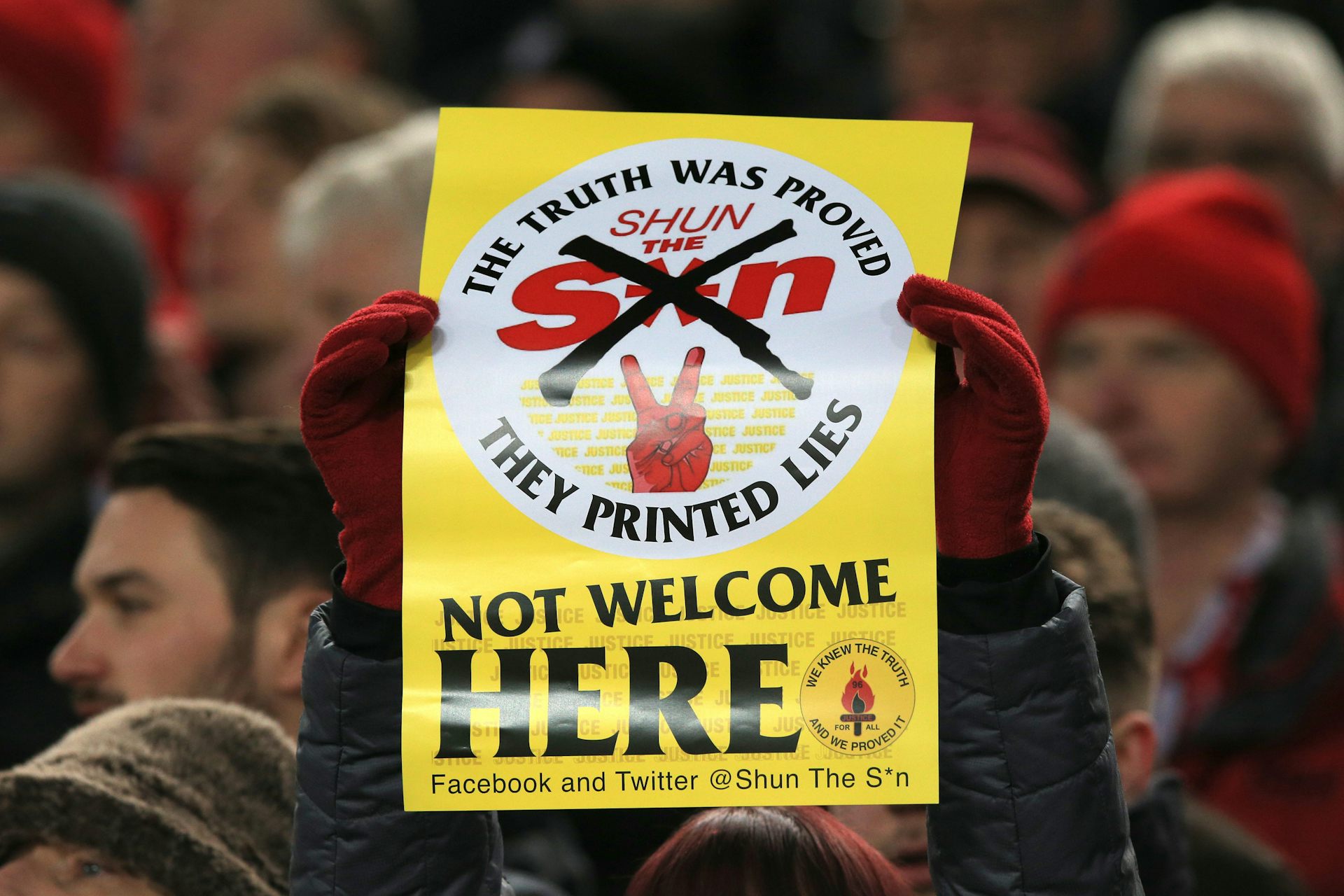 A Liverpool fan holds up a yellow sign proclaiming the Sun not welcome here