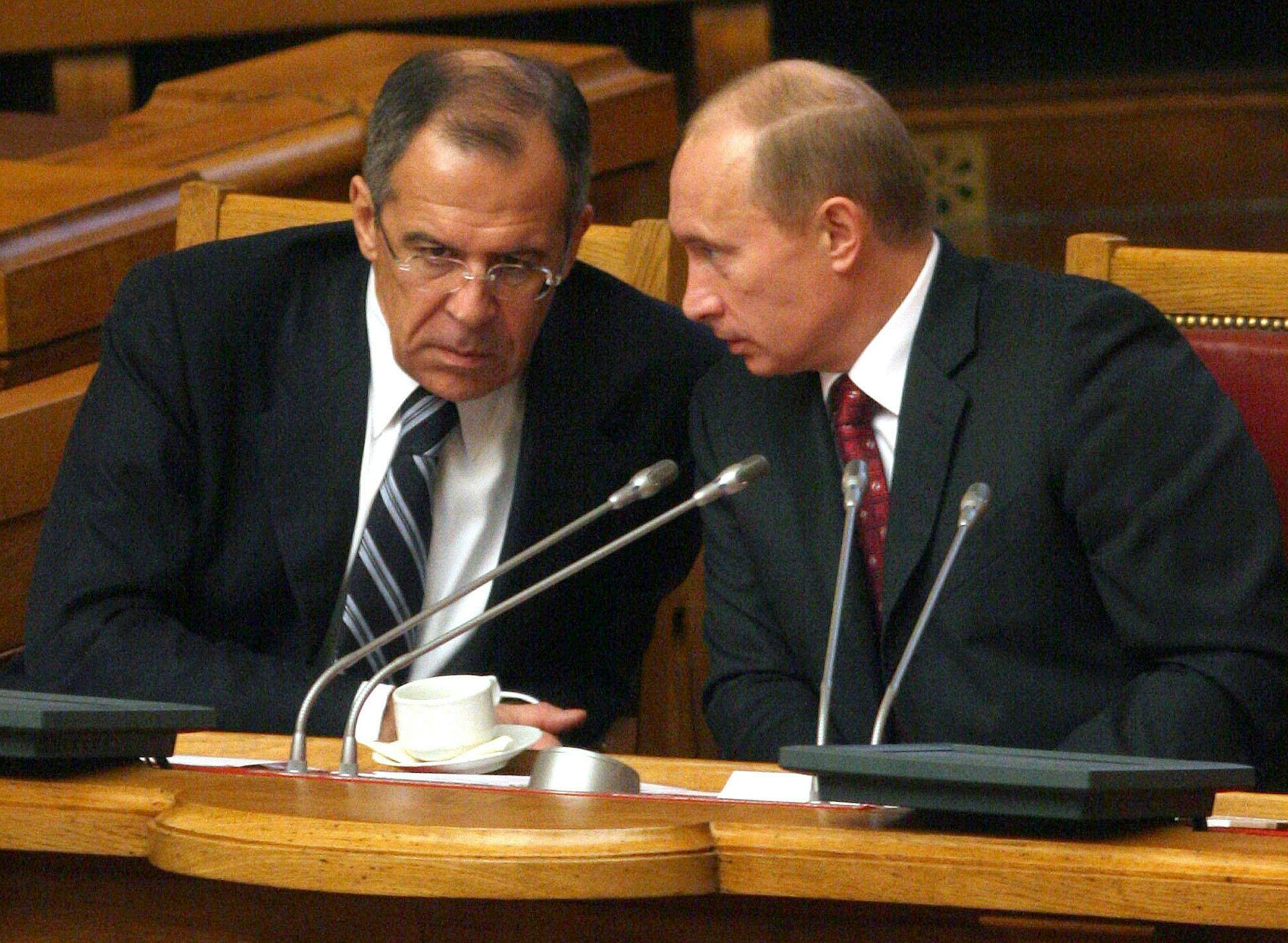 Russian president Vladlmir Putin and foreign secretary Sergey Lavrov talk with their heads together.