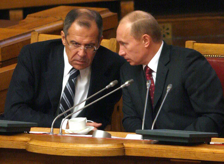 Russian president Vladlmir Putin and foreign secretary Sergey Lavrov talk with their heads together.