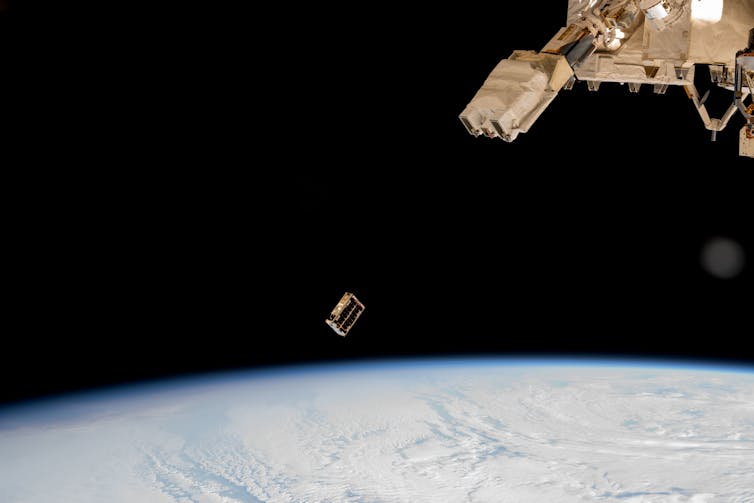 A small boxlike satellite ejected into orbit around Earth from a larger spacecraft.