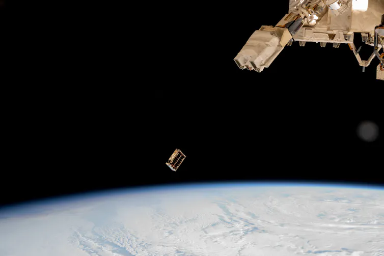 A small boxlike satellite ejected into orbit around Earth from a larger spacecraft.