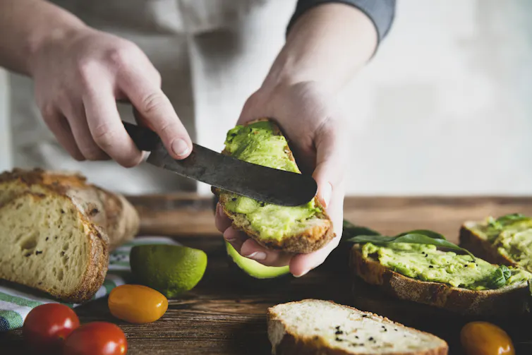 Person spreads avocado on toast.