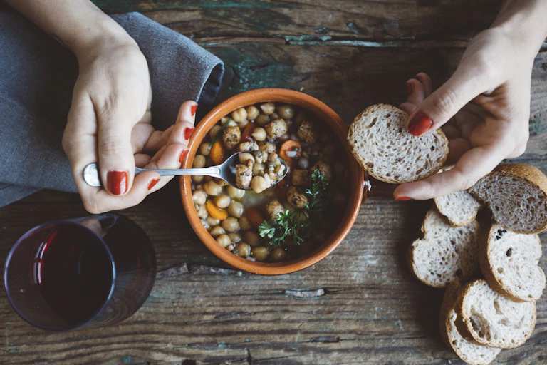 A woman eats bean stew with bread.