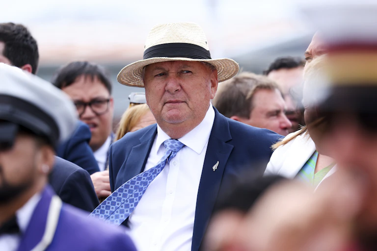 Man in suit, tie and hat standing among a crowd of people