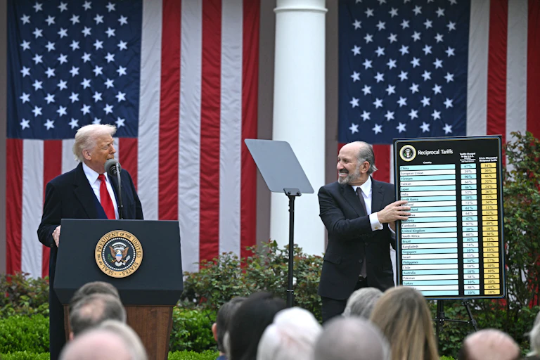 US President Donald Trump delivers remarks on reciprocal tariffs as US Secretary of Commerce Howard Lutnick holds a chart during an event in the Rose Garden