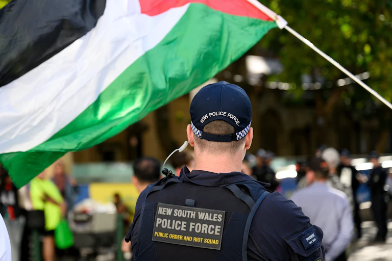 The back of a NSW police officer under a Palestinian flag