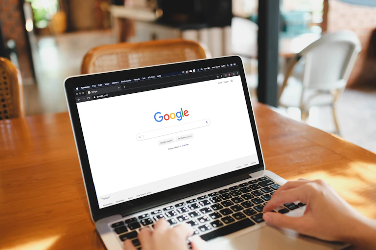A man is typing on Google search engine from a laptop.