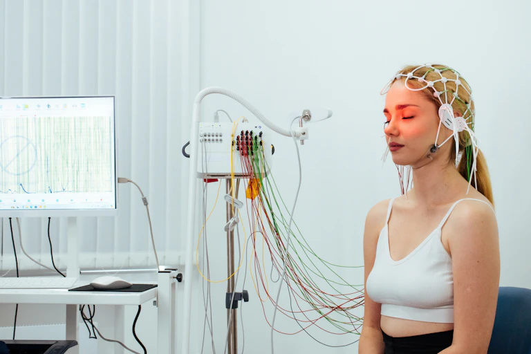 Una mujer con sensores en la cabeza, conectados con cables a un aparato