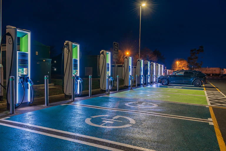 A row of charging points in a service station car park at night.