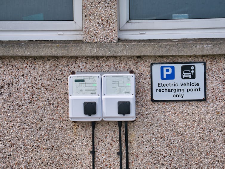 A pebble-dash wall with an EV charge point on it.