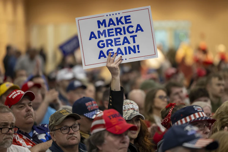 A crowd of people with one holding a sign that says "Make America Great Again!"