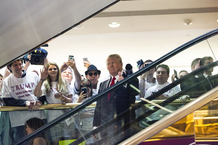 A man descends an escalator as other people watch.
