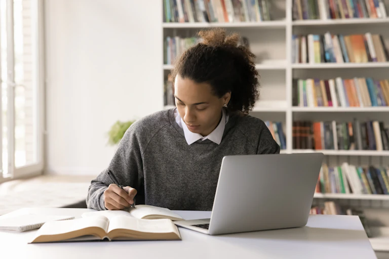 Una joven estudio con libros y un ordenador portátil