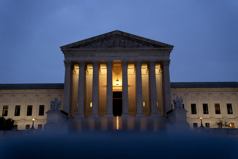 A federal building with columns is seen at dusk.