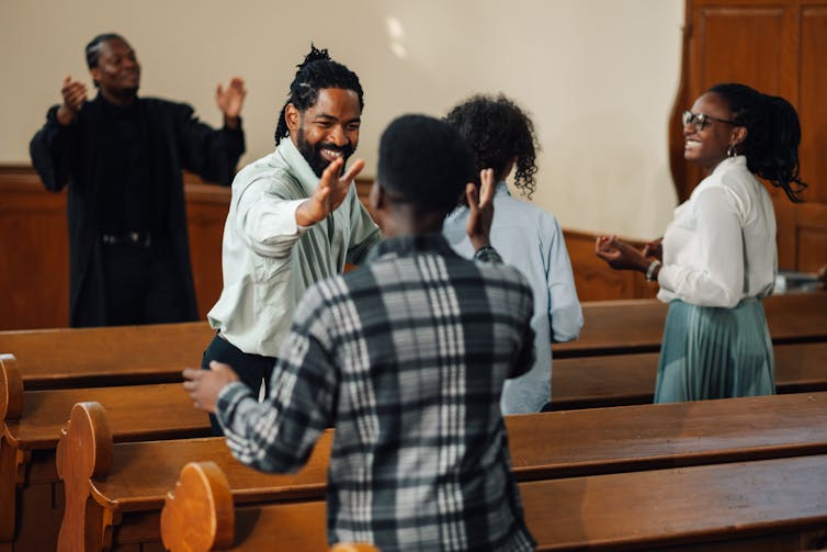 People smiling and shaking hands while standing in pews in a church