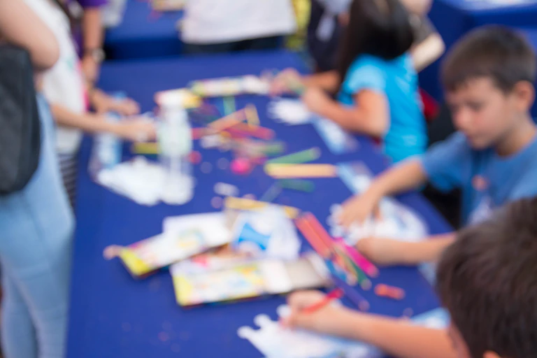 A blurred image shows kids drawing and painting at childcare.