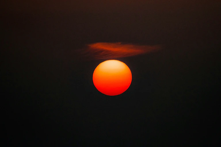 A burning red circle against a black sky.