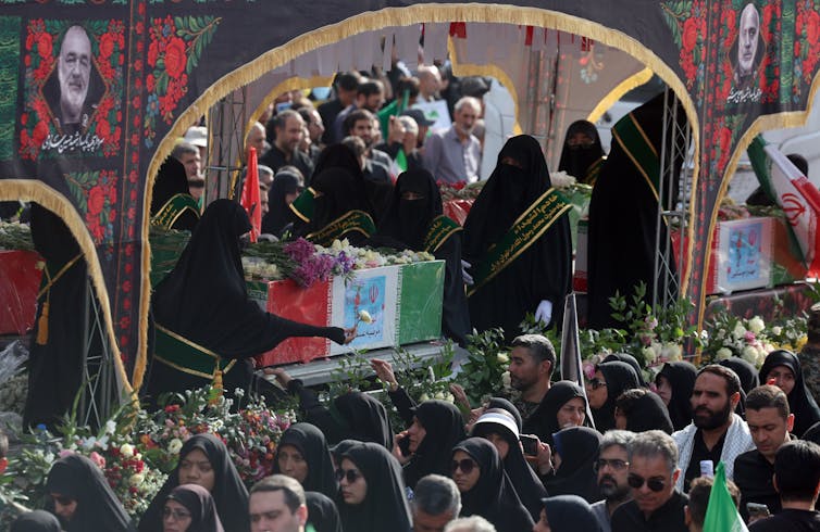 A crowd of Iranians gather aroud a coffin at a public funeral for a general killed by an Israeli strike, June 2025