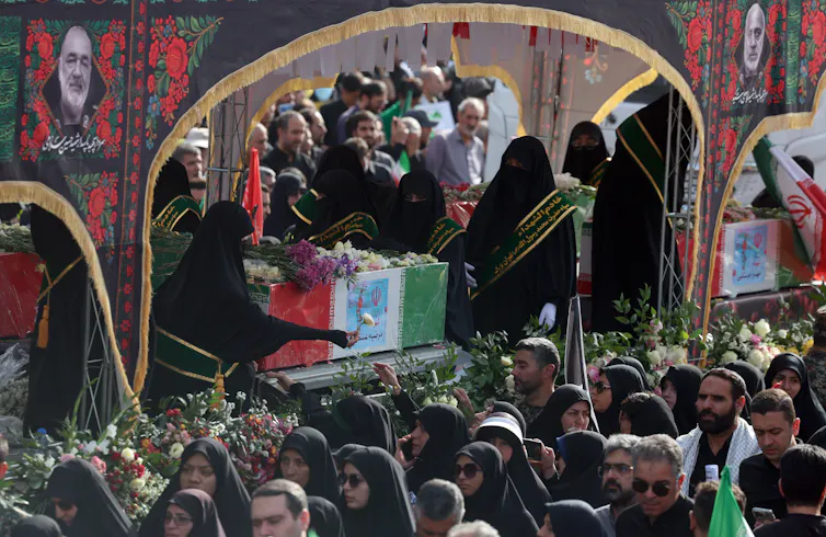 A crowd of Iranians gather aroud a coffin at a public funeral for a general killed by an Israeli strike, June 2025