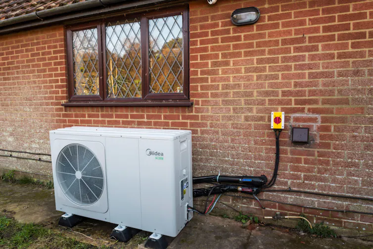 A large white box with a fan plugged into the exterior of a house.