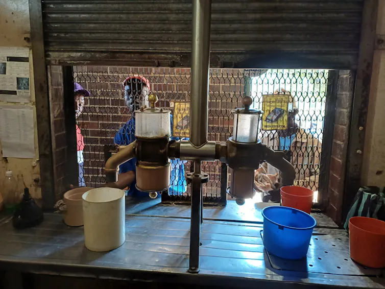Men are seen taking beer from behind a metal grille.