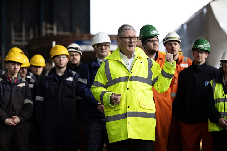 Keir Starmer in high-viz standing in front of a group of men in hard hats.