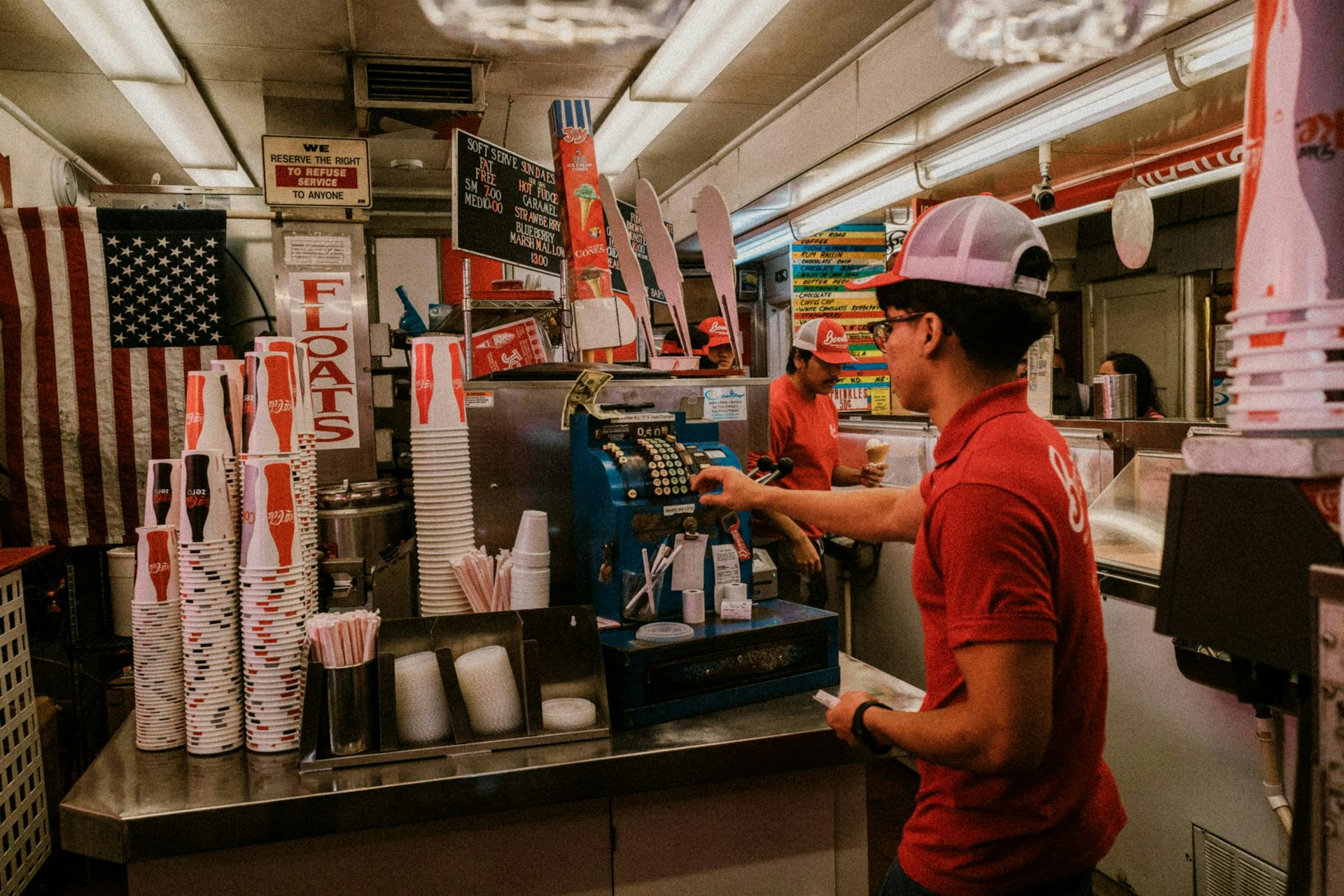 Un jeune homme en train de remplir un verre de boisson gazeuse, dans un restaurant fast-food