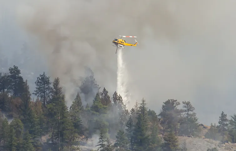 Un hélicoptère largue de l’eau sur un incendie de forêt