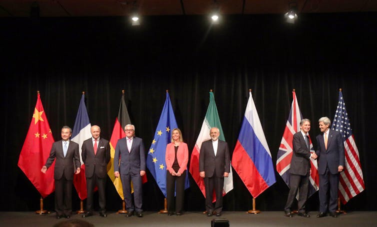 People post on stage next to flags.