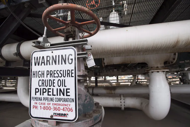 A sign on a pipe that says 'Warning High Pressure Crude Oil Pipeline'