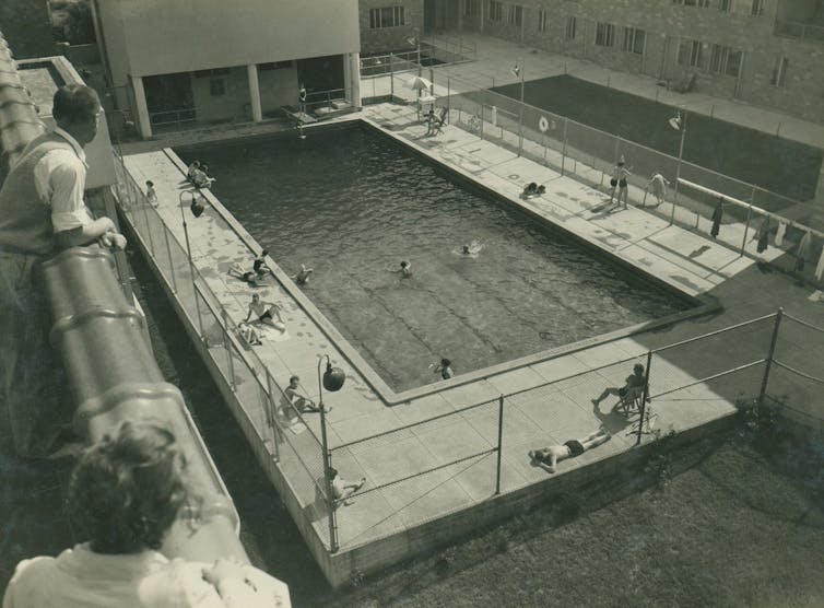 Black and white photo of a swimming pool surrounded by an apartment complex.