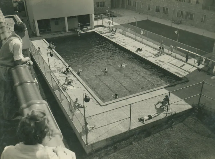 Black and white photo of a swimming pool surrounded by an apartment complex.
