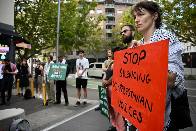 A protest sign reads: 'stop silencing pro-Palestinian voices'.