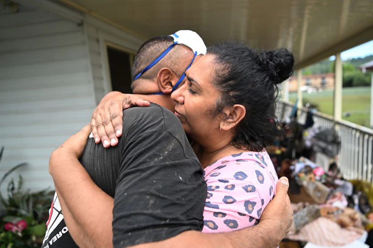 A woman in a pink top hugs a man