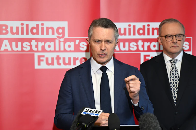 Man in a suit stands in front of a sign saying "Building Australia's Future"