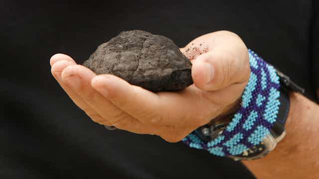 A man holds a potato-sized nodule brought up from the sea floor.