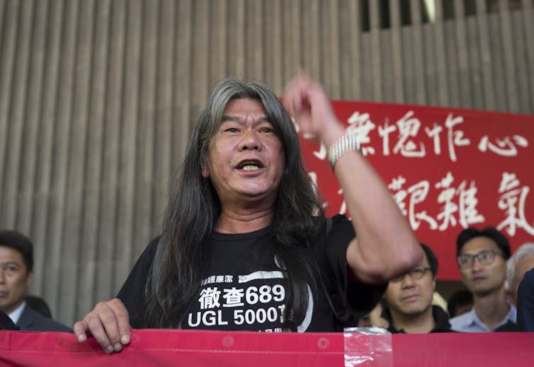 Smiling, long haired Leung Kwok-hung at a protest in Hong Kong