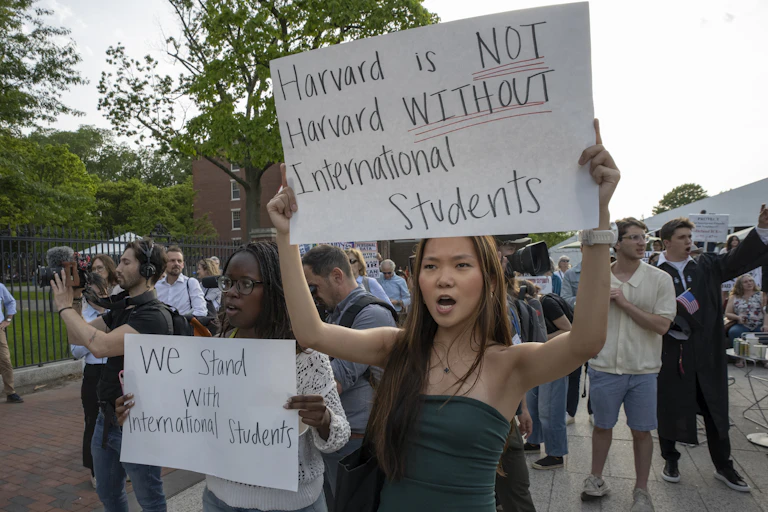 young people at a protest holding up signs supporting international students