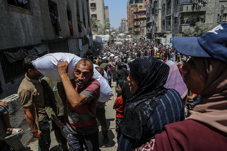 Huge crowd of Palestinians queuing for supplies food as some receive sacks of food.