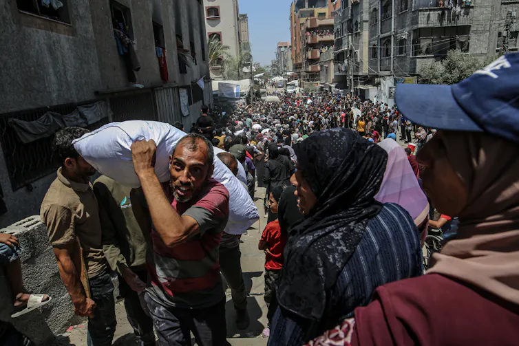 Huge crowd of Palestinians queuing for supplies food as some receive sacks of food.