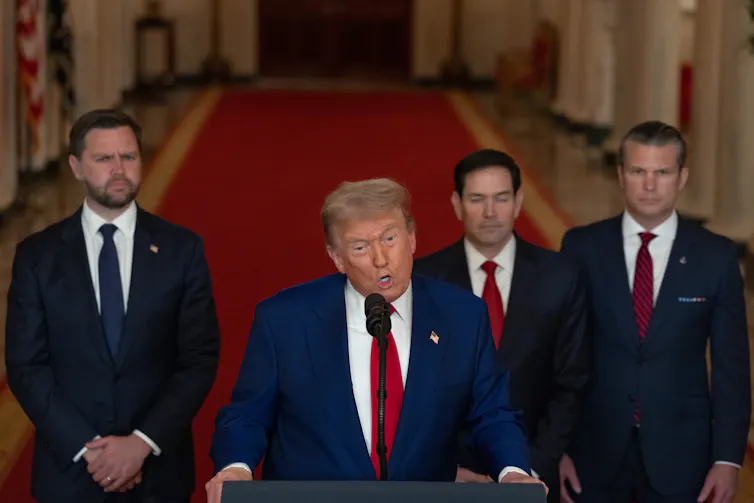 Donald Trump flanked by senior aides speaks at a podium in the White House, June 22 2025.