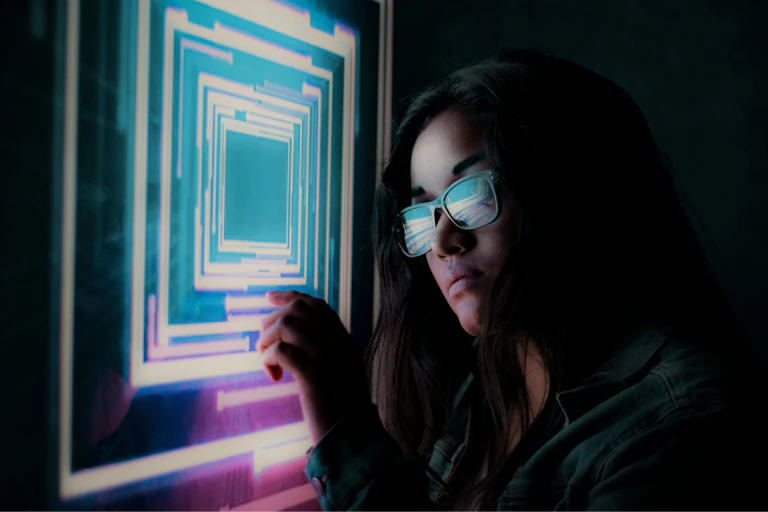 Woman wearing glasses and looking at neon lights.