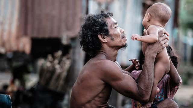 An Orang Asli father holding his baby.