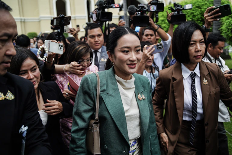 A woman in a green suit is flanked by other people.