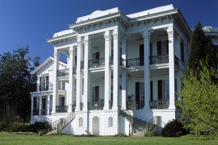 A white mansion on a green lawn.