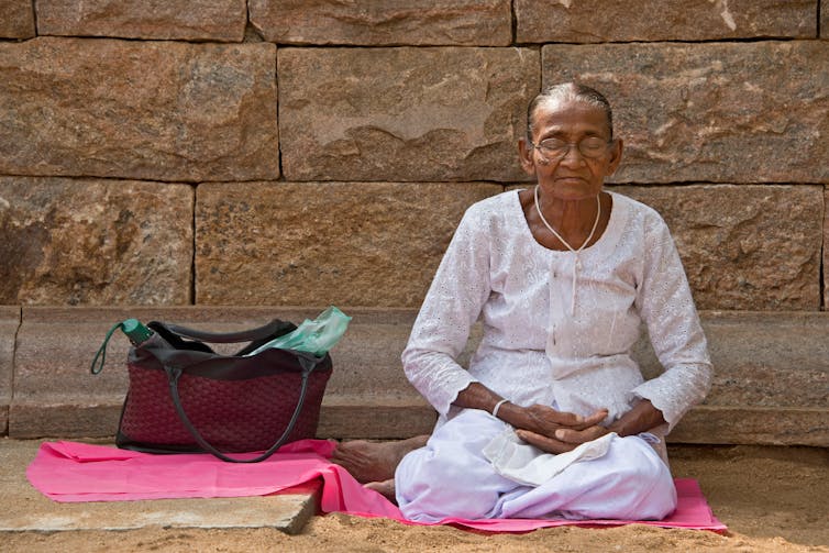 An elderly woman meditating.