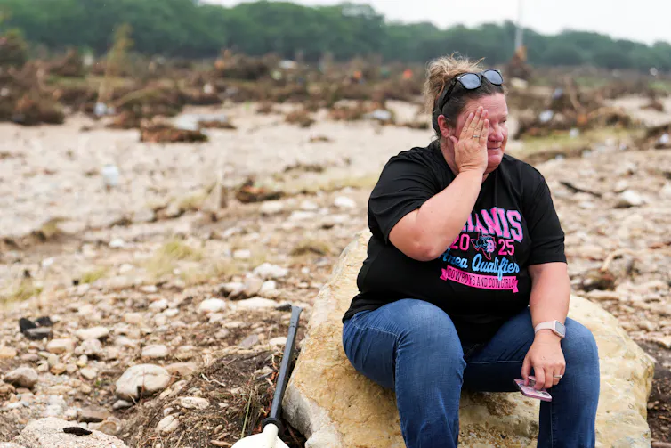 A woman takes a moment while searching for survivors along the Guadalupe River in Texas.