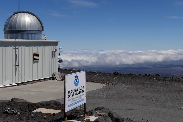 A steel building with domed roof and a sign saying Manua Loa Observatory